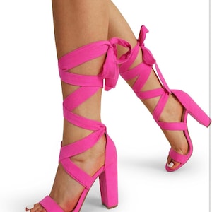 May include: Pink high-heeled sandals with a thick block heel and multiple straps that tie up the leg.