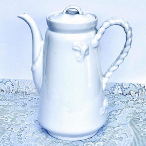 Cafetera antigua de Limoges con detalles náuticos en relieve y asa trenzada. Decoración playera. Tetera blanca para brunch nupcial. Mesa de postres para bodas.