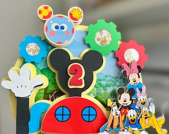 May include: A colourful Mickey Mouse Clubhouse cake topper featuring Mickey Mouse, Minnie Mouse, Donald Duck, Goofy, and Pluto. The topper includes a red house with two windows, a yellow background, and the text "Matteo's Clubhouse".
