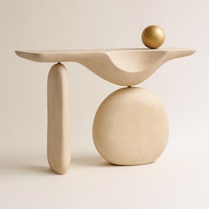 Può includere: Una consolle moderna e astratta in un colore beige neutro. Il tavolo presenta un piano curvo con un accento a sfera dorata, sostenuto da una colonna verticale e una base arrotondata. Il design è minimalista e scultoreo.