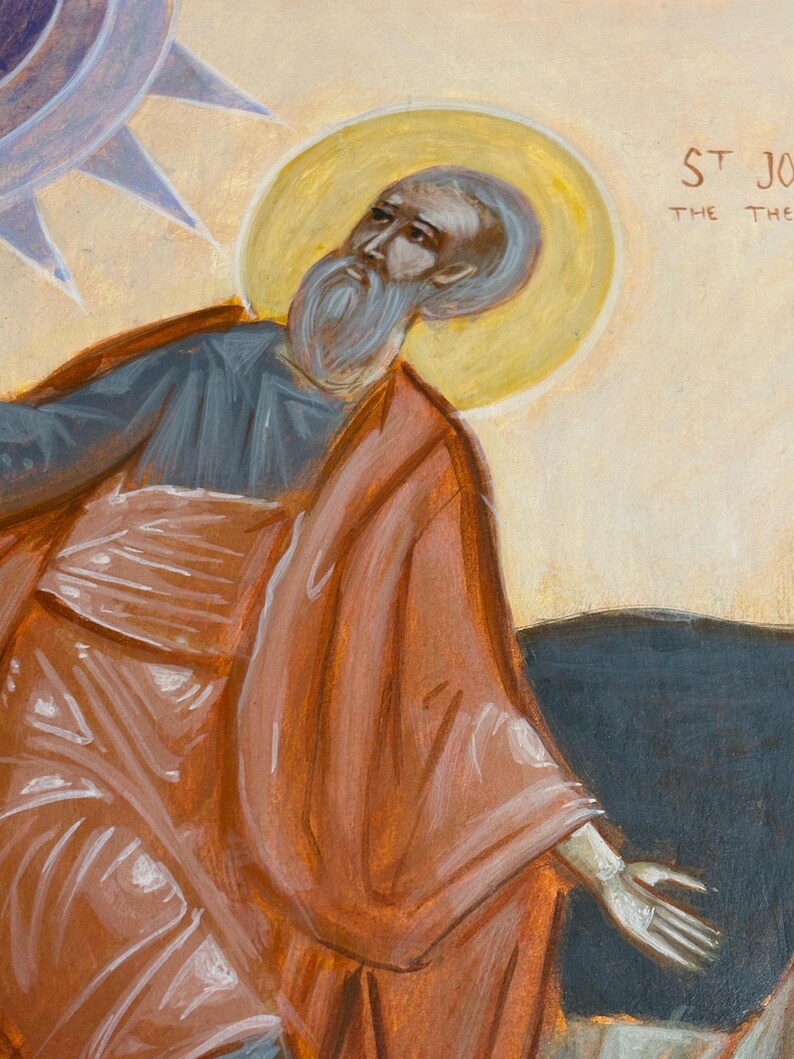 May include: An icon painting of a saint with a long white beard, wearing a red robe and a blue undergarment. A yellow halo surrounds the saint's head. The background is a light beige color with the text "ST JO" visible.