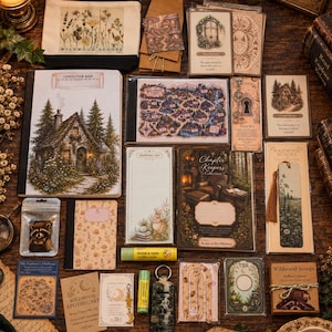 May include: A collection of stationery items including a composition book with a cottage illustration, a map of Wildwood Forest, various bookmarks, a shopping list pad, a small pouch, lip balms, a raccoon charm, and cards featuring woodland themes.