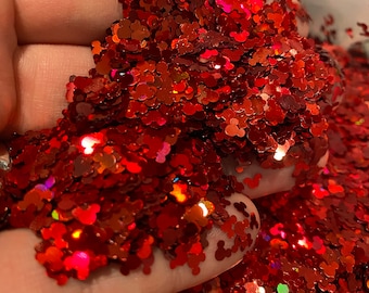 May include: Red glitter in the shape of Mickey Mouse heads. The glitter is iridescent and has a holographic finish.