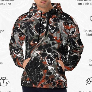 May include: A black and orange marbled hoodie with a relaxed fit and drop shoulders. The hoodie has a double-lined hood with a design on both sides, black premium drawstrings, and a brushed fleece fabric inside. The care label is tear away and the fabric face has a soft cotton feel.