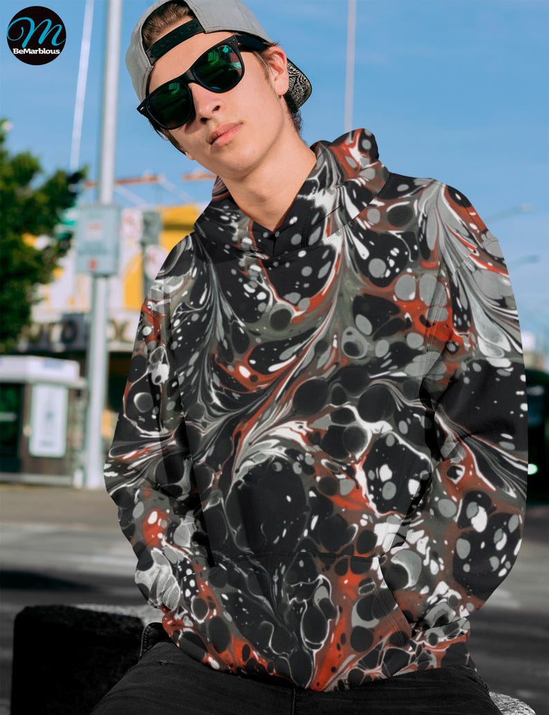 May include: A black hoodie with a red, white, and gray marbled pattern. The hoodie has a drawstring hood and a kangaroo pocket.