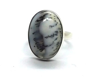 May include: A silver ring with a white and black dendritic agate oval stone.
