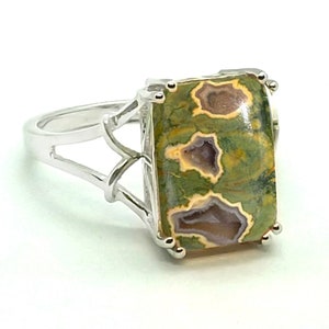 May include: A silver ring with a green, brown, and white jasper stone set in a rectangular shape.