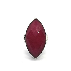 May include: A silver ring with a large, faceted, red gemstone in the shape of a marquise.