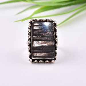 May include: A silver ring with a rectangular black and white patterned stone set in a beaded frame.