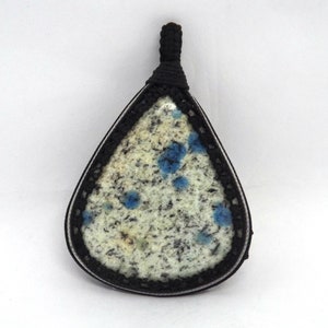 Può includere: Un ciondolo a forma di lacrima con un cordoncino nero e una pietra blu e bianca incastonata in una cornice argentata.