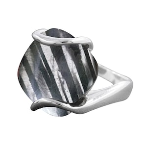 Puede incluir: Un anillo de plata con una piedra preciosa rayada en blanco y negro. El anillo tiene un diseño único con la banda envolviendo la piedra.