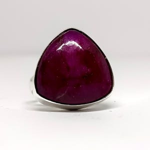 Könnte beinhalten: Ein silberner Ring mit einem großen, dreieckigen, tiefvioletten Edelstein.