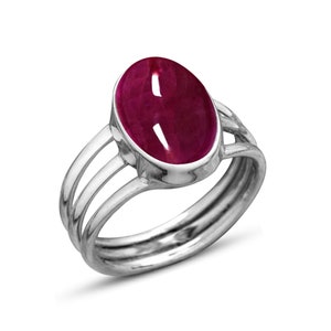 May include: A silver ring with a deep red oval gemstone set in a bezel setting. The ring band has three thin bands.