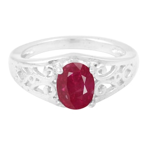 May include: A silver ring with a red oval gemstone set in a filigree design.