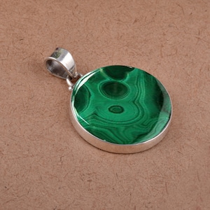 May include: A silver pendant with a round green malachite stone. The stone has a swirling pattern of green and black.