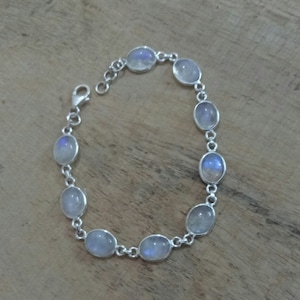 May include: A silver bracelet with oval-shaped moonstone beads. The bracelet has a lobster claw clasp.