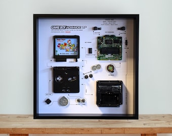 Oprawiona w czarną ramę grafika demontowana na GameBoy Advance SP: retro konsola do gier