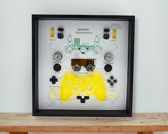 Arte emoldurada de um controle DualShock do PS2 amarelo transparente: Caixa de sombra para gamer desmontado