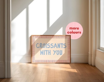 May include: A framed print with a light beige background and red and white stripes around the border. The text "CROISSANTS WITH YOU" is written in blue on the print.