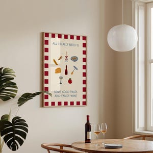 May include: A framed poster with a cream background and red checkered border. The poster features illustrations of pasta, wine, and related items. Text on the poster reads "ALL I REALLY NEED IS SOME GOOD PASTA AND FANCY WINE."