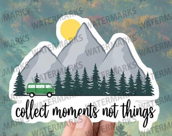 May include: A sticker with a green van driving through a forest with mountains in the background. The sun is shining and the text "collect moments not things" is written below the van.