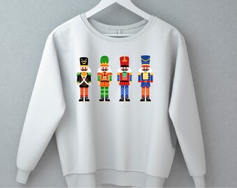 May include: A light gray sweatshirt with a graphic of four colorful nutcracker soldiers. The nutcrackers are wearing different colored hats and uniforms.