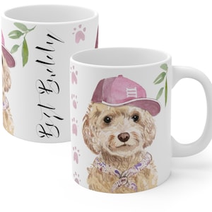 May include: White ceramic mug with a watercolor illustration of a dog wearing a pink baseball cap and a bandana. The text "Best Buddy" is written on the mug.