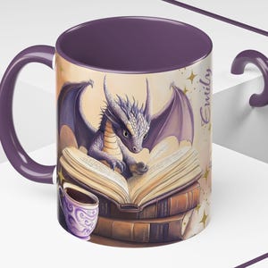 Puede incluir: Taza de cer&aacute;mica morada con un drag&oacute;n leyendo un libro y una taza de caf&eacute;. La taza tiene el nombre "Emily" escrito en el lateral.