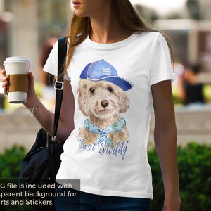 Può includere: Maglietta bianca con un'illustrazione ad acquerello di un cane che indossa un berretto da baseball blu e un bandana blu e verde. Il testo "Best Buddy" è stampato sotto il cane.