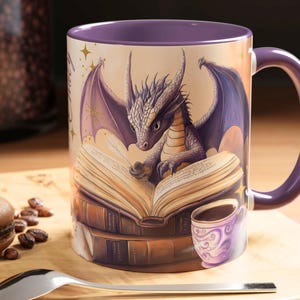 Puede incluir: Taza de cer&aacute;mica morada con un drag&oacute;n leyendo un libro. El drag&oacute;n es morado y tiene detalles dorados. El libro est&aacute; abierto y tiene una pluma en la parte superior. Hay otros libros apilados debajo del libro abierto. La taza tiene un asa morada.