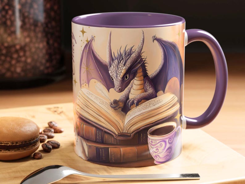 Puede incluir: Taza de cer&aacute;mica morada con un drag&oacute;n leyendo un libro. El drag&oacute;n es morado y tiene detalles dorados. El libro est&aacute; abierto y tiene una pluma en la parte superior. Hay otros libros apilados debajo del libro abierto. La taza tiene un asa morada.