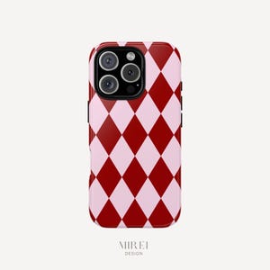 May include: A red and pink diamond pattern phone case for an iPhone. The case has a raised camera bump and a black border.