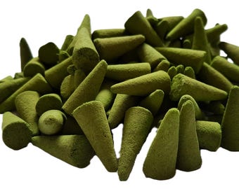 Può includere: Un grande mucchio di piccoli coni di incenso di colore verde oliva opaco. Ogni pezzo presenta una base circolare piatta e una punta superiore, con una superficie strutturata e polverosa coerente in tutta la collezione di oggetti.