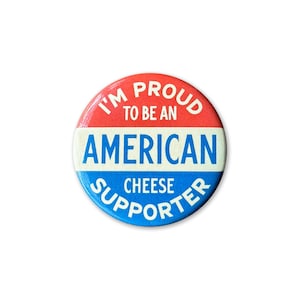 May include: A red, white, and blue button with the text "I'm Proud to Be an American Cheese Supporter".