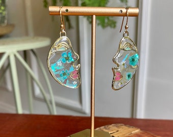 Orecchini viso astratti con fiori secchi e sfondo iridescente