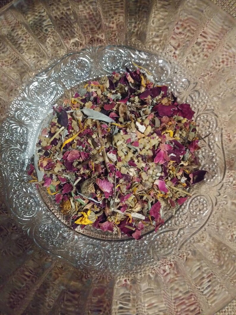 May include: A glass bowl filled with a mixture of dried herbs, flowers, and petals. The mixture includes dried rose petals, lavender, and other herbs. The bowl is decorated with a floral pattern.