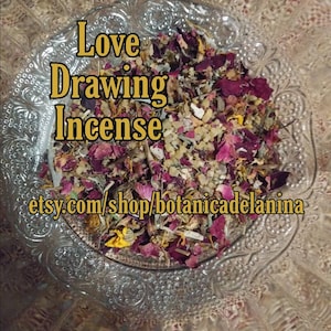 May include: A glass bowl filled with a blend of dried herbs, flowers, and crystals for love drawing incense. The mixture includes dried rose petals, yellow flowers, and white crystals. The text "Love Drawing Incense" is written in gold letters on the image. The text "etsy.com/shop/botanicadelanina" is also included in the image.