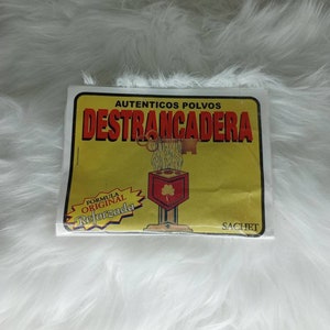 May include: A yellow and white packet of "AUTENTICOS POLVOS DESTRANCADERA"  powder. The packet has a picture of a key and a lock with the text "FORMULA ORIGINAL REFORZADA" and "SACHET".