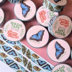 Puede incluir: Surtido de rollos de cinta washi coloridos con diseños de mariposas. Cada rollo mide 10 metros de largo y 1,5 centímetros de ancho. La cinta está etiquetada como "Washi Tape" y "Drawn to Nature".