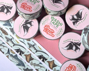 May include: Assortment of washi tape rolls featuring a marine life theme. The tape is 10 meters long and 1.5 centimeters wide. The rolls have a white background with black and white illustrations of sharks, rays, and other sea creatures. The text on the rolls reads "Washi Tape" and "Drawn to Nature".