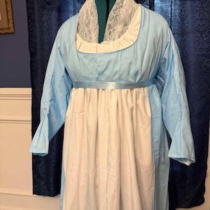 May include: A light blue dress with a white lace collar and a white underskirt. The dress has a fitted bodice and a flowing skirt.