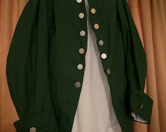 May include: A dark green long-sleeved jacket with a white shirt underneath. The jacket has a stand-up collar and a row of silver buttons down the front.