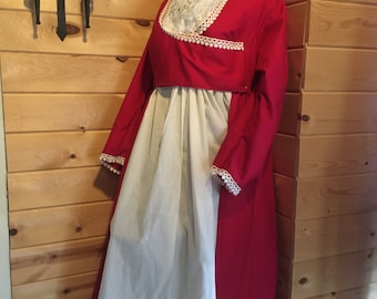 May include: A red and white dress with a lace collar and trim. The dress is on a mannequin and is displayed against a wood panel wall.