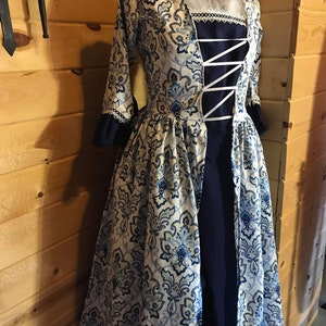 May include: A white and blue patterned dress with a navy blue bodice and white lace trim. The dress has a fitted bodice and a full skirt.