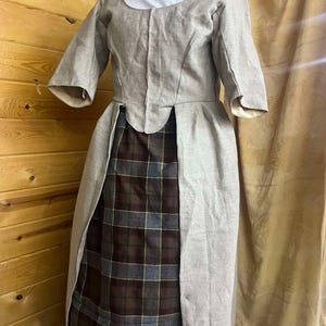 May include: A beige linen dress with a white undershirt and a plaid skirt underneath. The dress has a scoop neckline and 3/4 sleeves.