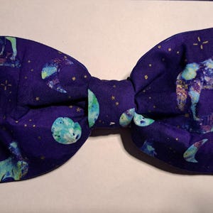 May include: A purple bow tie with a celestial pattern featuring moons, stars, and a galaxy-like design.