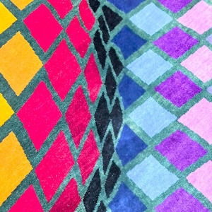 Puede incluir: Primer plano de un patr&oacute;n geom&eacute;trico colorido. El dise&ntilde;o presenta filas de rombos en amarillo, naranja, rosa, morado, azul y negro, delineados en verde oscuro. El patr&oacute;n es vibrante y llamativo.