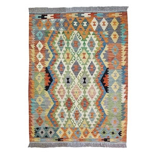 Könnte beinhalten: Ein rechteckiger, handgewebter Teppich mit einem geometrischen Rautenmuster. Der Teppich hat eine lebendige Farbpalette aus Orange, Blau, Grün und Creme. Die Kanten sind mit einem Fransen versehen. Dieser Teppich ist für Wohn- und Schlafzimmer geeignet.