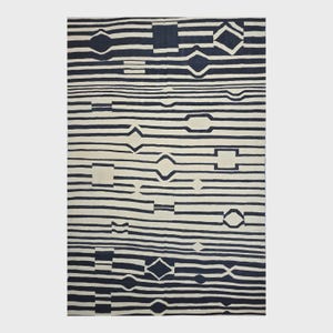 Pu&ograve; includere: Un tappeto rettangolare con sfondo color crema e un motivo a strisce orizzontali blu navy. Le strisce sono interrotte da varie forme geometriche, tra cui diamanti, quadrati e rettangoli. Il tappeto ha un design moderno e astratto.