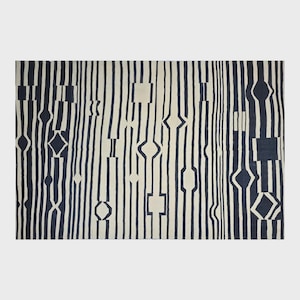 Pu&ograve; includere: Un tappeto rettangolare con sfondo color crema e strisce verticali blu navy. Le strisce sono intervallate da forme geometriche, tra cui quadrati, diamanti e ovali allungati. Il tappeto ha un design moderno e astratto.